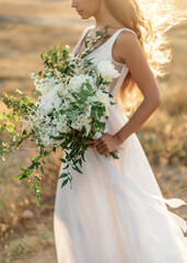 Close-up details of a wedding bouquet with wild flowers and white peonies in softlight focus.