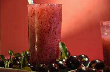 Jabuticaba juice on wooden surface on pink background