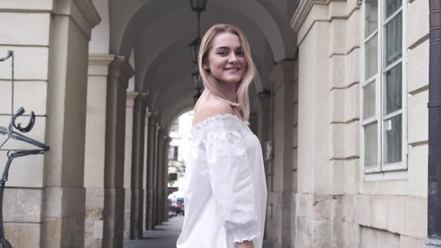 Beautiful girl fashion portrait with white dress walking on the street on old city. Pretty young woman in a white dress close up slow motion 4k.