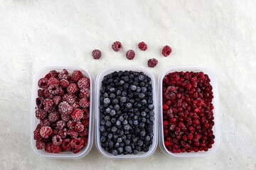 Frozen berries: blueberries, cranberries and raspberries on a grey background