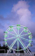 a colourfully illuminated Ferris wheel stands in front of a dark sky