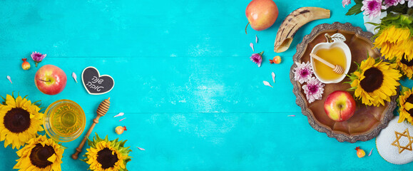 Jewish holiday Rosh Hashana background with honey, apples and sunflowers on blue wooden table. Top view from above