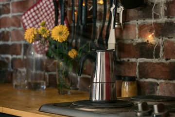 Fototapeta na wymiar geyser coffee maker is on the stove, coffee is brewed at home, a good morning begins with freshly brewed coffee. Loft design, red brick background