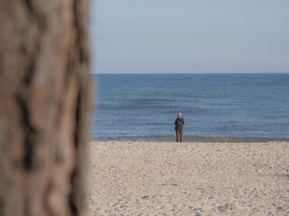  lonely man stands directly on the shore of a sea and looks at the water