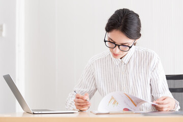 A businesswoman wearing glasses working with smiling and happiness at the office.