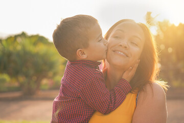 Young mother laughing and  carries her son in her arms - Child kiss his mother - Family, mother and...