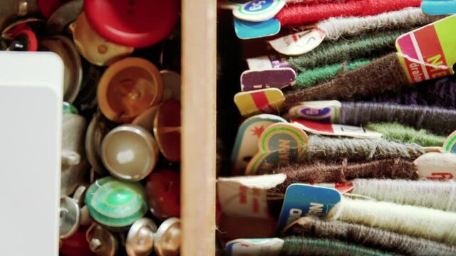 Big, colorful sewing kit with yarn and buttons in wooden box
