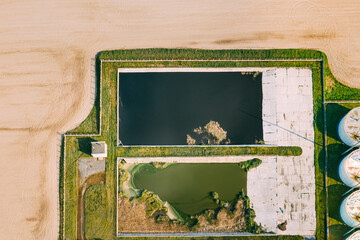 Aerial View Of Retention Basins, Wet Pond, Wet Detention Basin Or Stormwater Management Pond Near Biogas Bio-gas Plant From Pig Farm. Artificial Pond With Vegetation Around Perimeter.