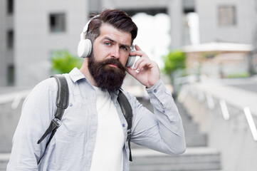 Daily route to work. Modern life. Man with headphones walking city center. Listening music. Handsome hipster with backpack walking street. Walking through empty streets. Alone with music. Good sound