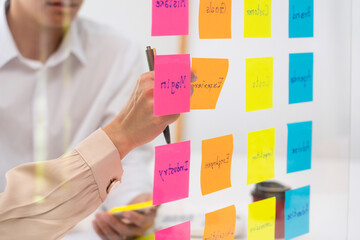 business people planning startup project placing sticky notes session to share idea on glass wall,...