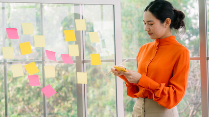 Business people work on project planning board in office and having conversation with coworker...