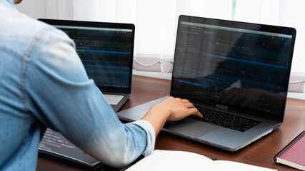 Programmer or software developer Typing New Lines of Code, coding technologies working at wooden industrial interior work place station.