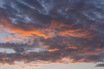 Naklejka na ściany i meble Chmury na niebie oświetlone czerwonym światłem zachodzącego słońca.