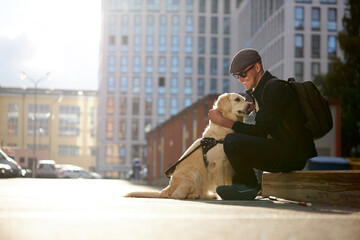handsome blind guy have rest with golden retriever in the city, young male sit with guide dog, love...