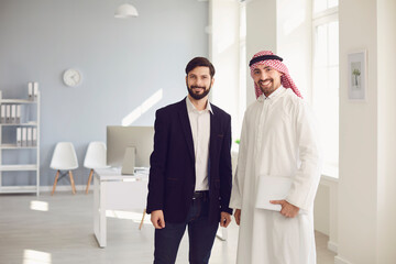 Arab and European business people are standing together in a modern office.