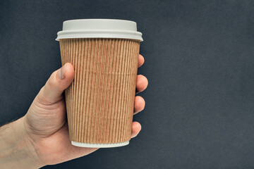 Paper cup in hand on a colored background. Eco-friendly materials in a coffee shop, biodegradable disposable tableware. Close up