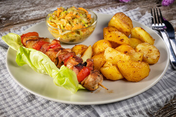 Shish kebab served with roasted potatoes and salad.
