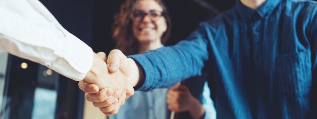 Business people shaking hands in the office. Finishing successful deal, meeting room conference. Wide screen, panoramic