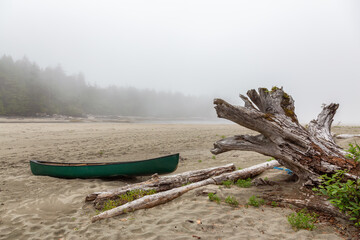 Canoe on a Sandy Beach during a foggy morning on the Pacific Ocean Coast. Taken at Raft Cove, Vancouver Island, British Columbia, Canada.
