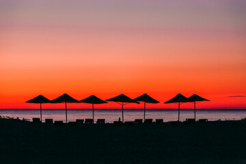 Beach umbrellas on sea at sunrise
