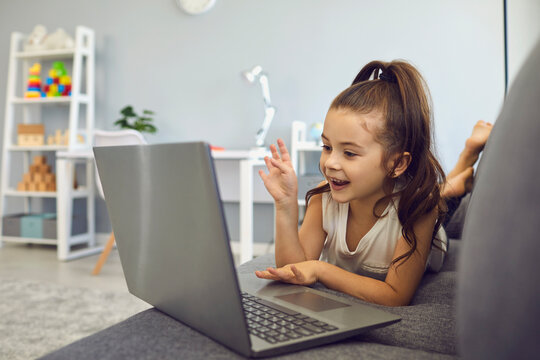 Little Girl Talking To Family, Friend Or School Teacher Online From Home. Lovely Kid Using Laptop For Communication