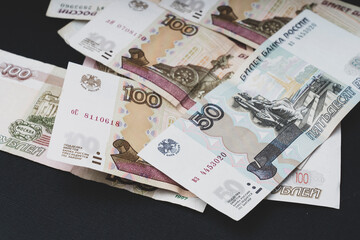 Russian hundred-ruble bills on a dark background, the concept of the Russian economy's recession, selective focus