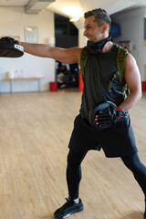 Motivated boot camp instructor stands with punch mitts in gym hall. Training with extended arm on...