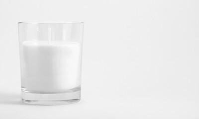 White candle in transparent glass on white background, mock up