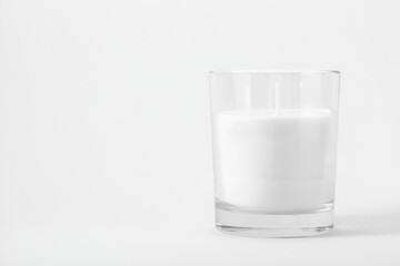 White candle in transparent glass on white background, mock up