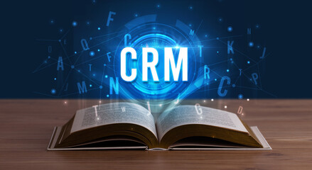 CRM inscription coming out from an open book, digital technology concept