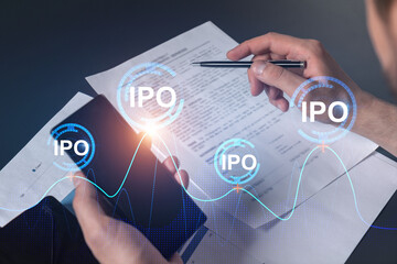Double exposure of man signing contract with phone and ipo hologram. Concept of initial primary...