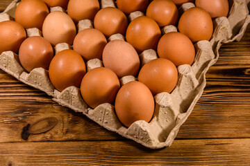 Pile of the hen eggs in paper tray on wooden table