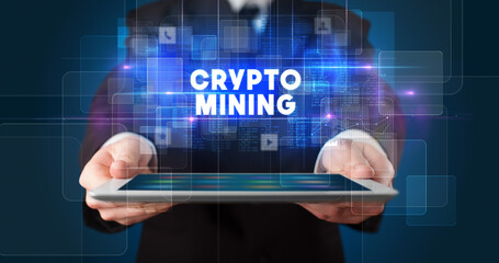 Young business person working on tablet and shows the inscription: CRYPTO MINING