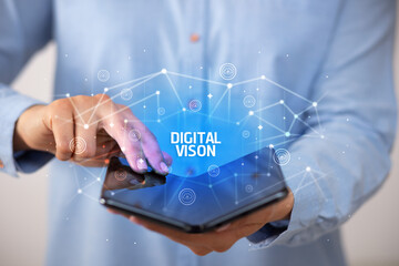 Businessman holding a foldable smartphone with DIGITAL VISON inscription, new technology concept