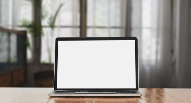 Blank screen computer laptop is putting on a wooden table over the living room as a background.