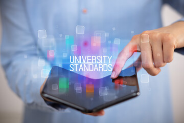 Young man holding a foldable smartphone with UNIVERSITY STANDARDS inscription, educational concept