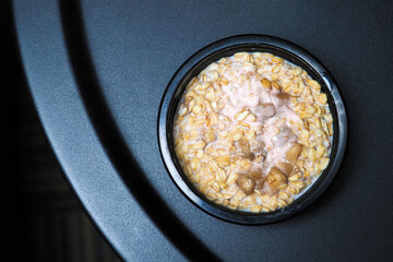 Healthy breakfast. Oat flakes muesli with fruit in yogurt, top view, black table