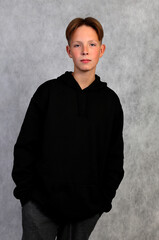 A boy in a black sweatshirt on a gray background.