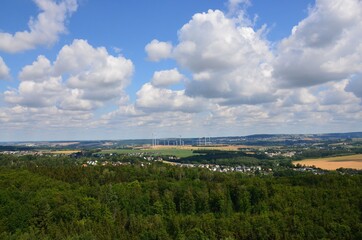 Fototapeta na wymiar Ausblick über Wald und Hügellandschaft im Sommer mit Wolkenhimmel