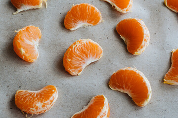 Tangerine slices on grey Kraft paper.