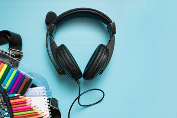 colored pencils, markers, school briefcase, school supplies and headphones on a blue background....