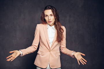 Adult woman with shrug gesture on dark background