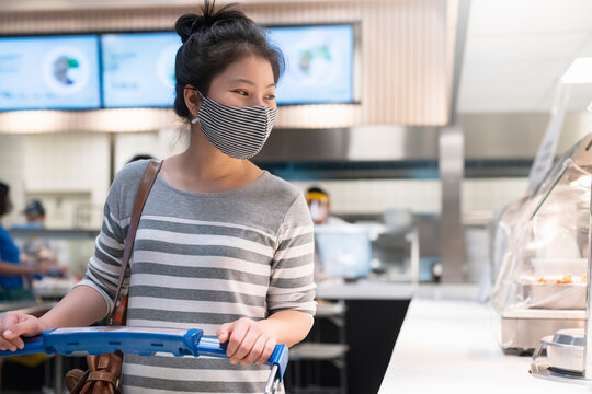 New normal lifestyle young asian female woman wear protective face mask walk in line wating for order food in food court department store mall