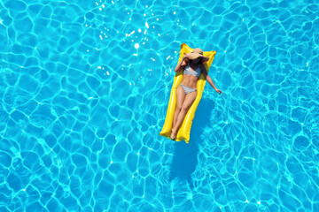 Young woman with inflatable mattress in swimming pool, top view