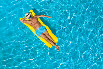 Young man with inflatable mattress in swimming pool, top view. Space for text