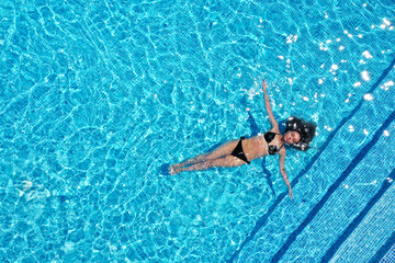 Beautiful young woman swimming in pool, top view. Space for text