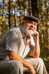 His new life as pensioner. Old pensioner relax in natue. Pensioner with grey beard hair in woods. Bearded man of pensioner age. Right to pension. Autumn of life