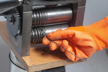 Jeweler at work, process rolling of a silver wire crafting in a jewelery workshop.