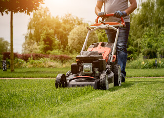 Gardener mowing the lawn. Landscape design. Green grass background - obrazy, fototapety, plakaty