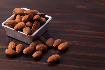 Almonds in a zinc cup on a wooden floor